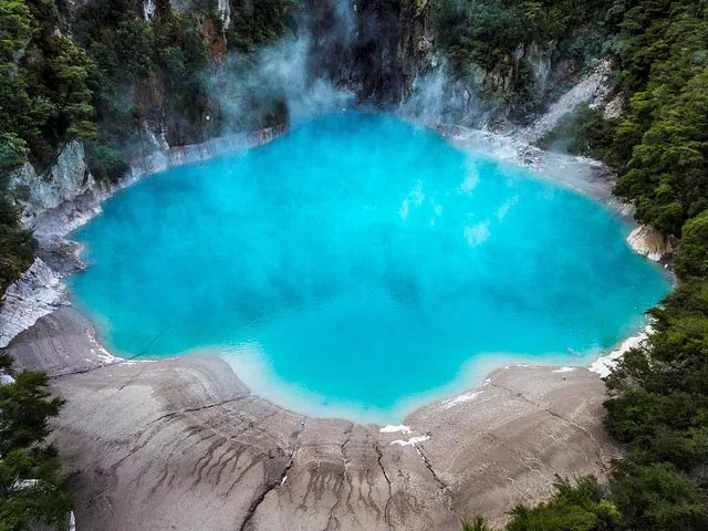 Un lago volcánico de color azul brillante que humea, rodeado de bosque en Waimangu Volcanic Valley