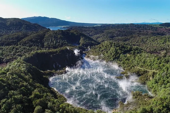 Luchtfoto van een stomend meer omringd door groen bos in Waimangu Volcanic Valley